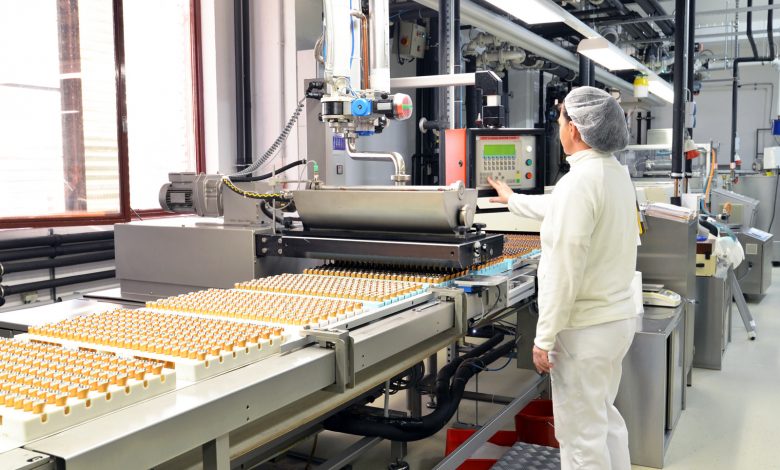 Alt="Production of pralines in a factory for the food industry - conveyor belt worker with chocolate"